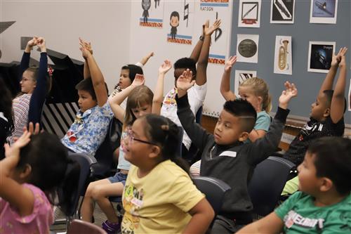 Dodge students raising their hands in music class